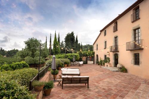 a patio with tables and chairs and a building at Can Mora de Dalt in Sant Vicenç de Montalt
