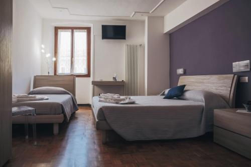 Una habitación de hotel con dos camas y un televisor. en Residenza al Castello, en Verona