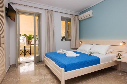 a bedroom with a bed with blue sheets and a balcony at Madena Apartments in Stoupa