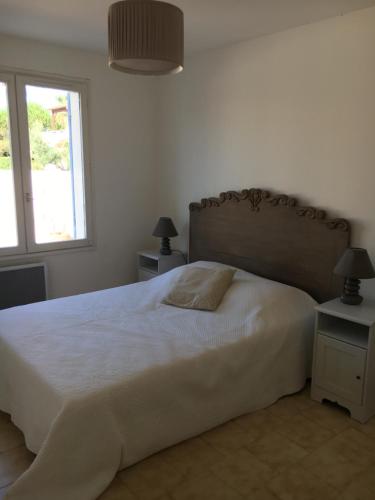 a bedroom with a large white bed with a window at Villa rapatel in Saint-Cyprien-Plage