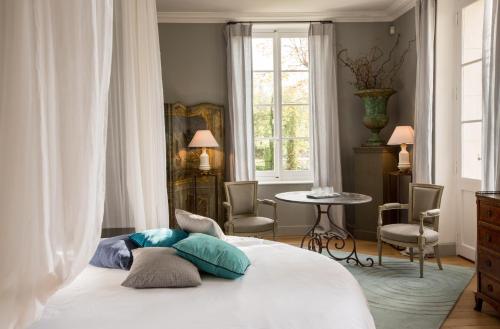 a bedroom with a bed and a table and a window at La Divine Com&eacute;die-Suites Deluxe in Avignon