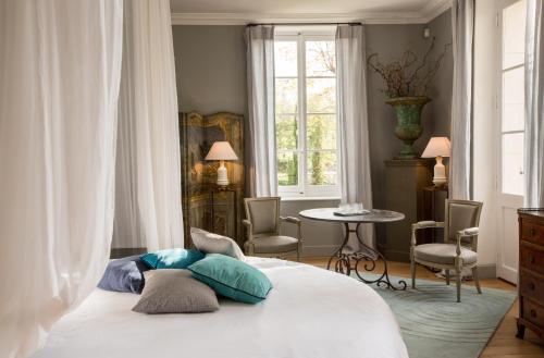 a bedroom with a bed and a table and a window at La Divine Comédie-Suites Deluxe in Avignon