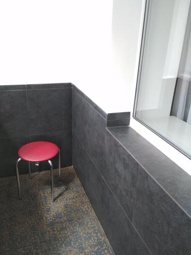 a red stool in a room with a window at New Apartment with 2 Isolated Bedrooms in Lviv