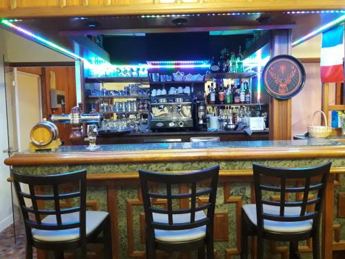 a bar with four chairs and a counter with alcohol at Chambres d'hôtes L'Astazou in Gavarnie