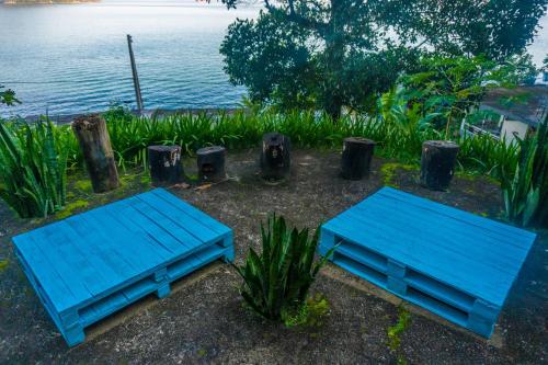 two blue benches sitting next to a body of water at Pousada Piquara in Mangaratiba
