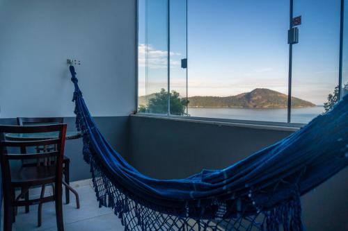 a hammock in a room with a view of the water at Pousada Piquara in Mangaratiba