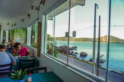 people sitting at tables in a restaurant looking out at the water at Pousada Piquara in Mangaratiba