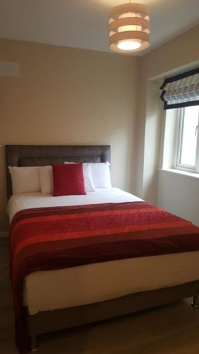 a bedroom with a large bed with a red pillow at St Bridget's Apartments in Galway