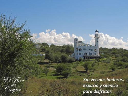 a building on a hill with a light house at El Faro de Carpier - ApartHotel & Restaurante Bar Cafetería in Tanti