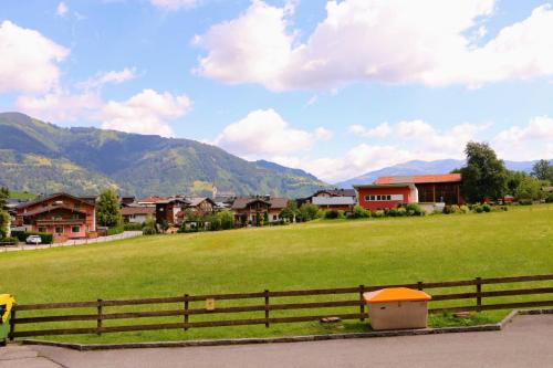 a field with houses and a fence and mountains at Green Wall Apartment Kaprun in Kaprun