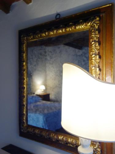 a picture of a bed with a lamp in front of a mirror at Bella di Ceciliano in Arezzo