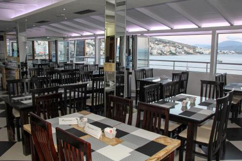 a restaurant with tables and chairs and a view of the water at Republika Hotel in Sarandë