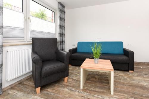 a living room with a couch and a chair and a table at Haus zur Möwe mit Frühstücksoption in Bensersiel