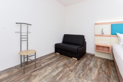 a bedroom with a black chair and a bed at Haus zur Möwe mit Frühstücksoption in Bensersiel