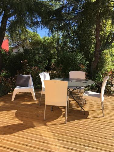 four chairs and a table on a wooden deck at Logis Hôtel O Lodge in Cleppé