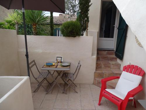 un patio avec une table, des chaises et un parasol dans l'établissement Syrah Grenache, à Montagnac