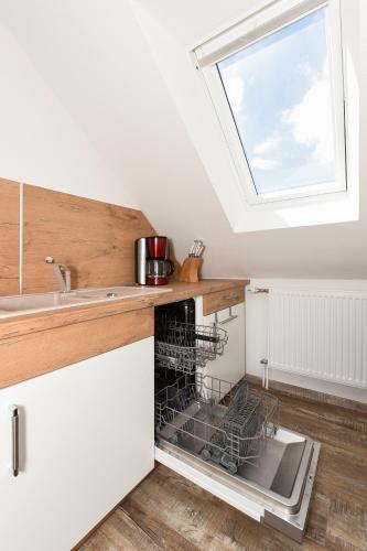 a kitchen with an open dishwasher with a window at Haus zur Möwe mit Frühstücksoption in Bensersiel