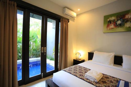 a bedroom with a bed and a view of a pool at Nyoman Villa Sanur in Sanur