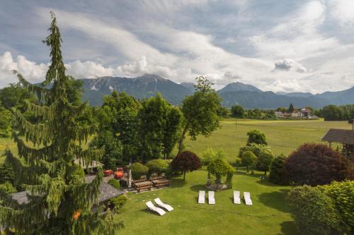 a garden with white chairs and trees and mountains at Apartment Wellness Essense in Bled