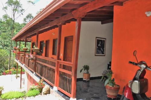 an orange house with a scooter parked in front of it at Hotel Orillas del Pizano in Jardin