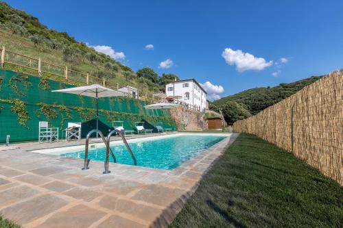 a swimming pool with an umbrella next to a house at B&B Pietra a Padule in Filettole