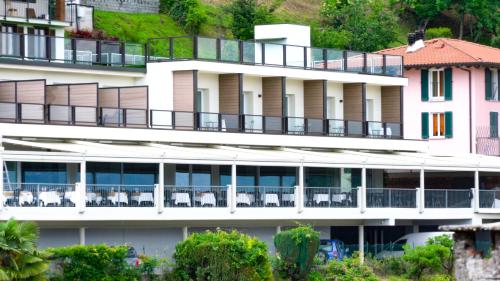 a large white building with balconies and tables and chairs at Stampa 1968 Hotel e Ristorante in Lavena Ponte Tresa