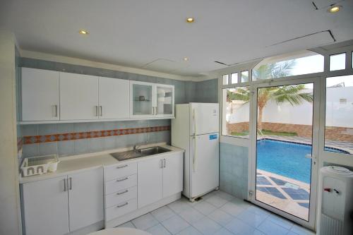 a kitchen with a sink and a refrigerator and a pool at دره العروس فيلا الاحلام للعائلات in Durat  Alarous