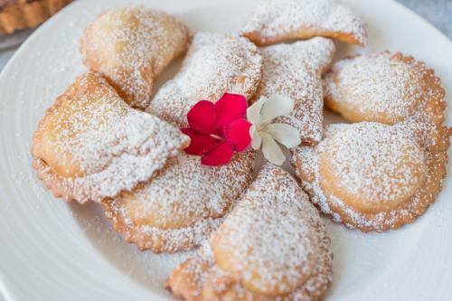 een bord met poedersuiker-donuts met een rode bloem erop bij Ciuri Di Mari in San Vito lo Capo