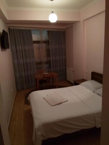 a bedroom with a bed and a table and a window at NNN Tourist in Kutaisi