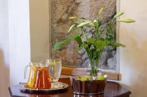a table with a vase with a plant and some drinks at De Hoek Manor in Stellenbosch