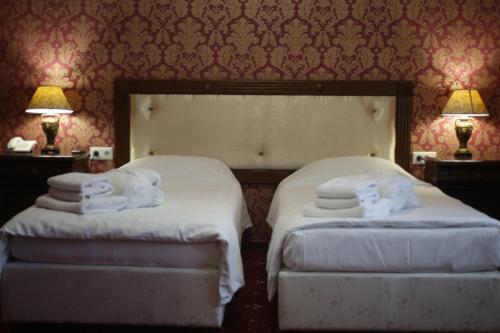 two beds in a hotel room with towels on them at Garden Hall in Ternopilʼ