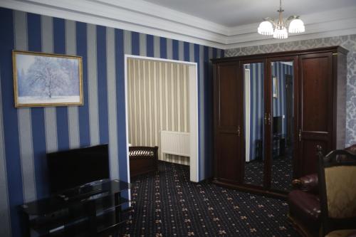 a hotel room with blue striped walls and a television at Garden Hall in Ternopilʼ