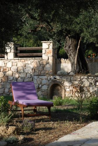 a purple chair sitting in front of a stone wall at LIORIZA Country Houses in Kalamaki