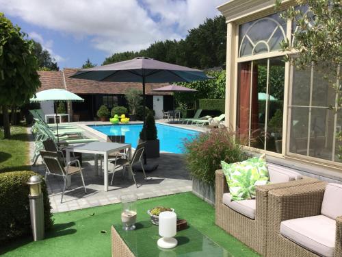 un patio trasero con piscina, mesa y sillas en Boutique hotel Het Bloemenhof, en Dudzele