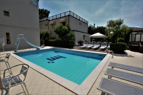 basen z krzesłami i budynek w obiekcie Hotel Marzia con Piscina w mieście Riccione