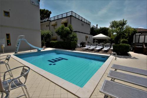 a swimming pool with chairs and a building at Hotel Marzia con Piscina in Riccione