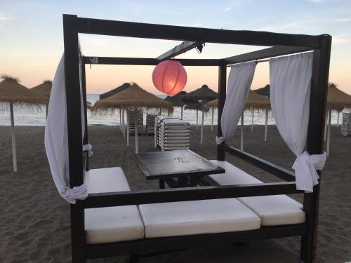 a bed on the beach with a table and umbrellas at Apartment with private patio in Fuengirola