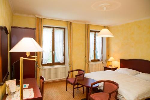 ein Hotelzimmer mit einem Bett, einem Tisch und Stühlen in der Unterkunft Hotel de Bahyse in Blonay