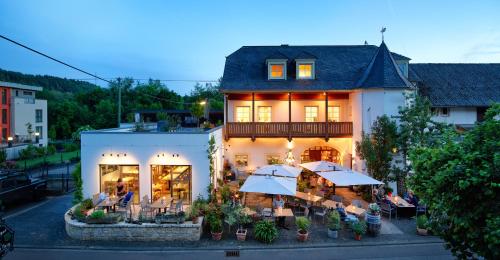 un edificio con tavoli e ombrelloni di fronte ad esso di Johannishof Wein-Café & Gästehaus a Mesenich