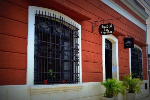 um edifício vermelho com um portão preto de ferro forjado em Hostal La Ermita em Mérida