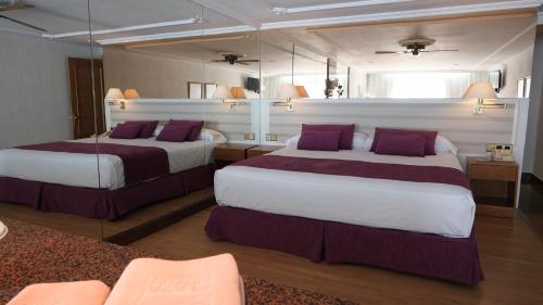 Habitación de hotel con 2 camas con almohadas moradas en Playacapricho en Roquetas de Mar