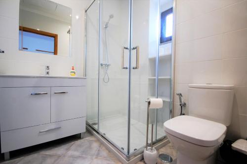 uma casa de banho branca com um chuveiro e um WC. em Vila Baltum - Free private parking - Wifi - Airco # by bedzy # em Albufeira