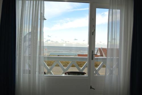 a window with a view of the ocean from a beach at Bed&Breakfast aan Strand in Katwijk aan Zee
