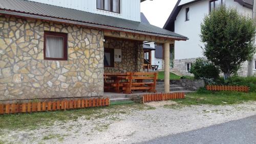 a stone house with a porch with a wooden bench at Apartments & Rooms Vitko in Žabljak