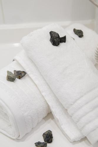 two towels with a bow tie and rocks on them at Amalia Rooms Sea View in Nea Vrasna