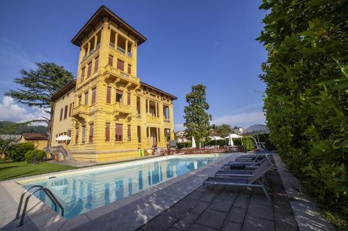 un edificio amarillo con una torre de reloj junto a una piscina en Villa Moorings, en Barga