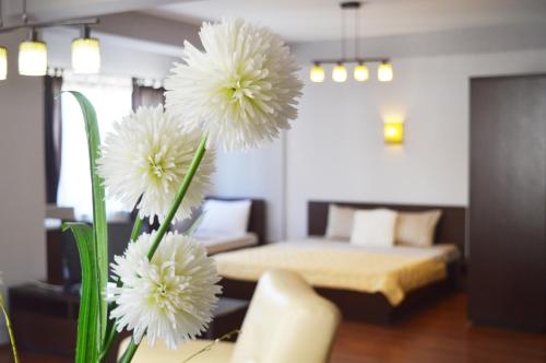 een kamer met een bed en een vaas met witte bloemen bij Antigona Apartments in Skopje