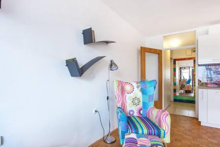 a living room with a chair and a lamp at Apartment Living Colors in Ljubljana