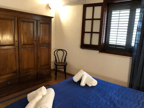 a bedroom with a blue bed and a chair at Villa Mariza in Scopello