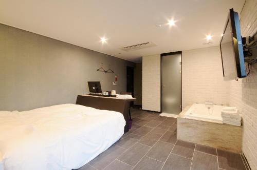 a hotel room with a bed and a bath tub at Queens Hotel Seomyeon Busan in Busan